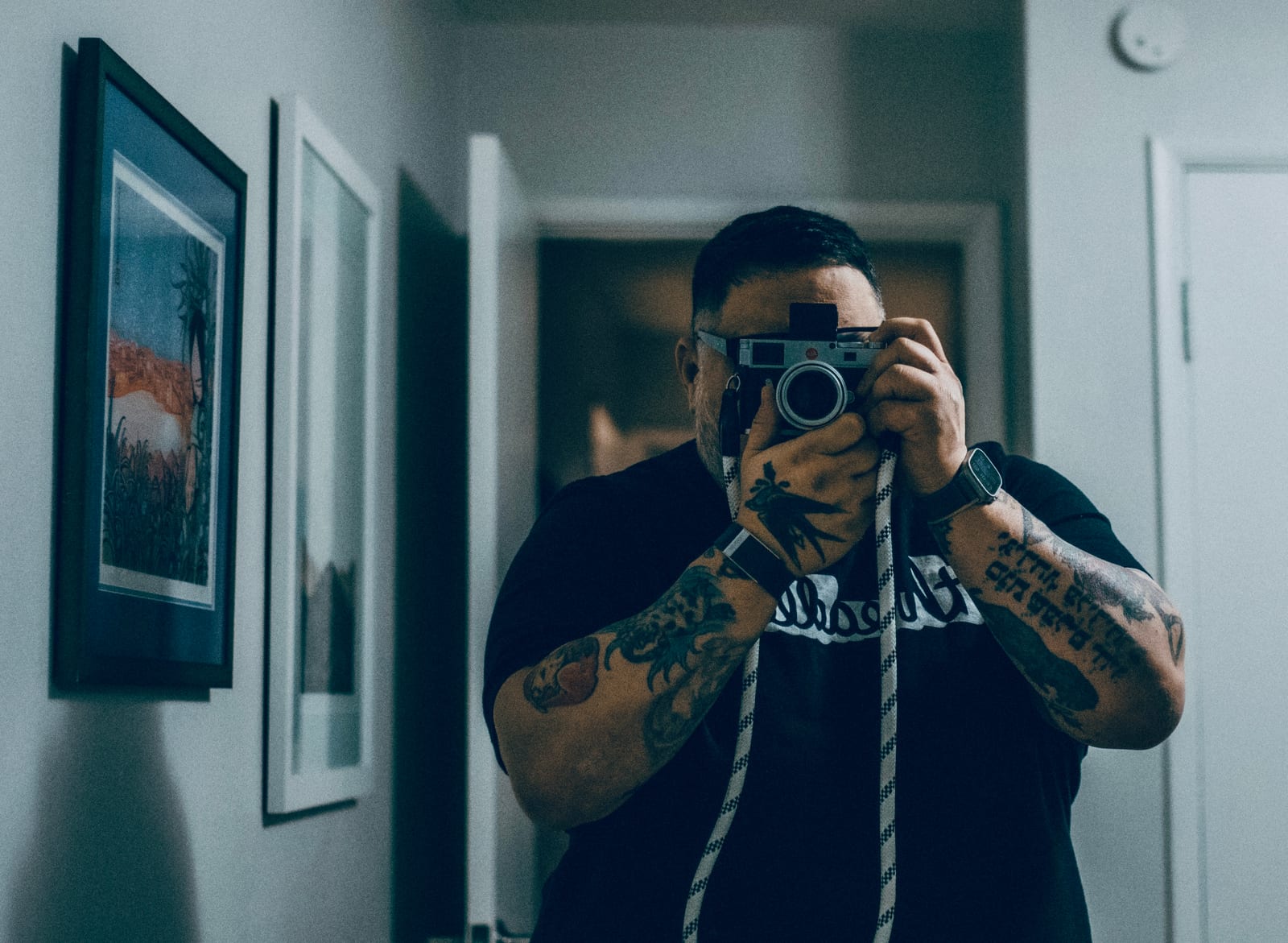 The photographer, self-portrait in a hallway mirror, holding a Leica.